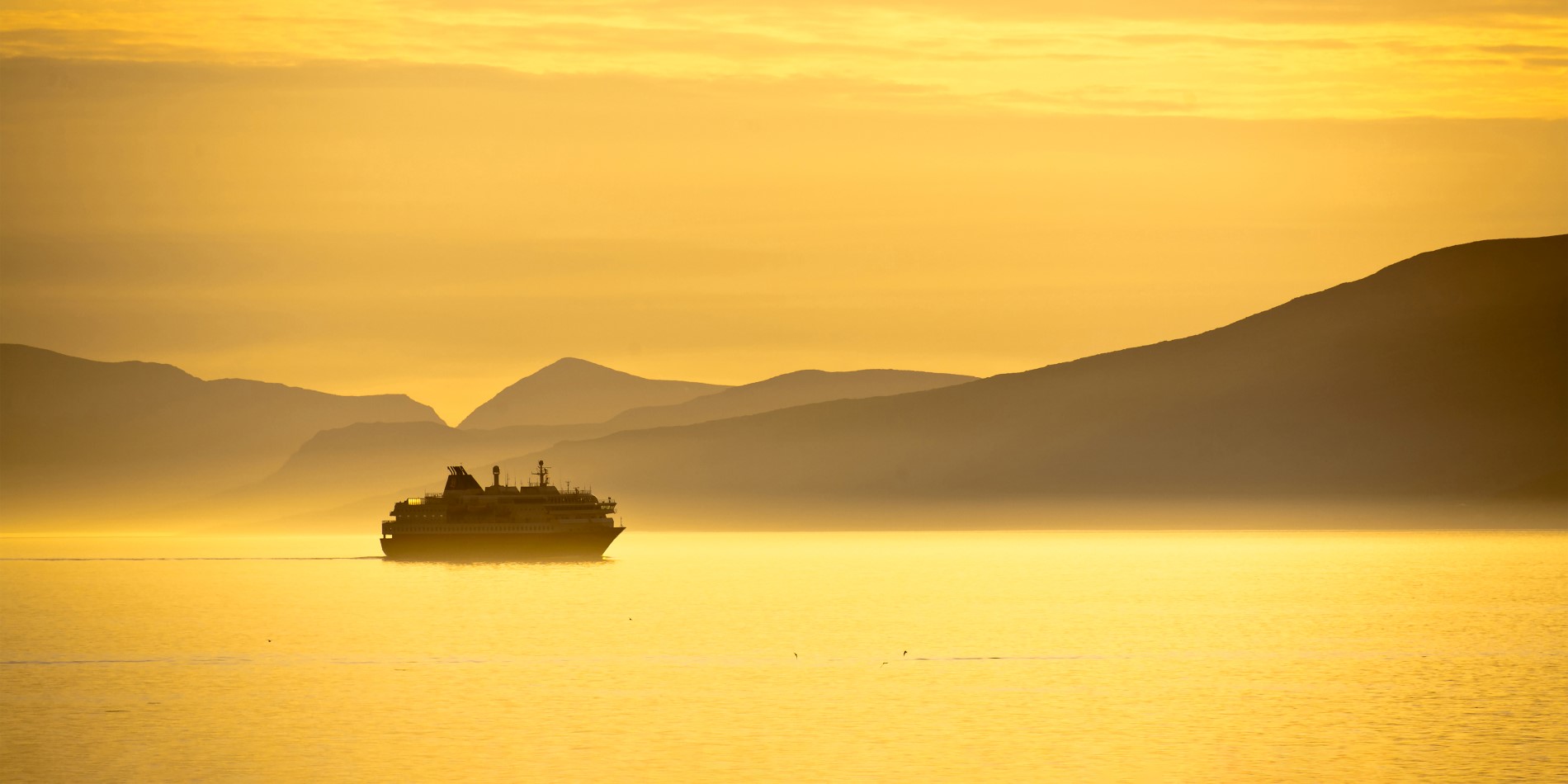 Hurtigruten sailing in the midnight sun - both the sky and water is bright yellow 