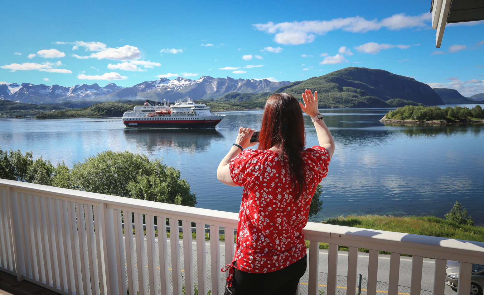 Eva Rendal standing in her house waiving to Hurtigruten who is sailing by