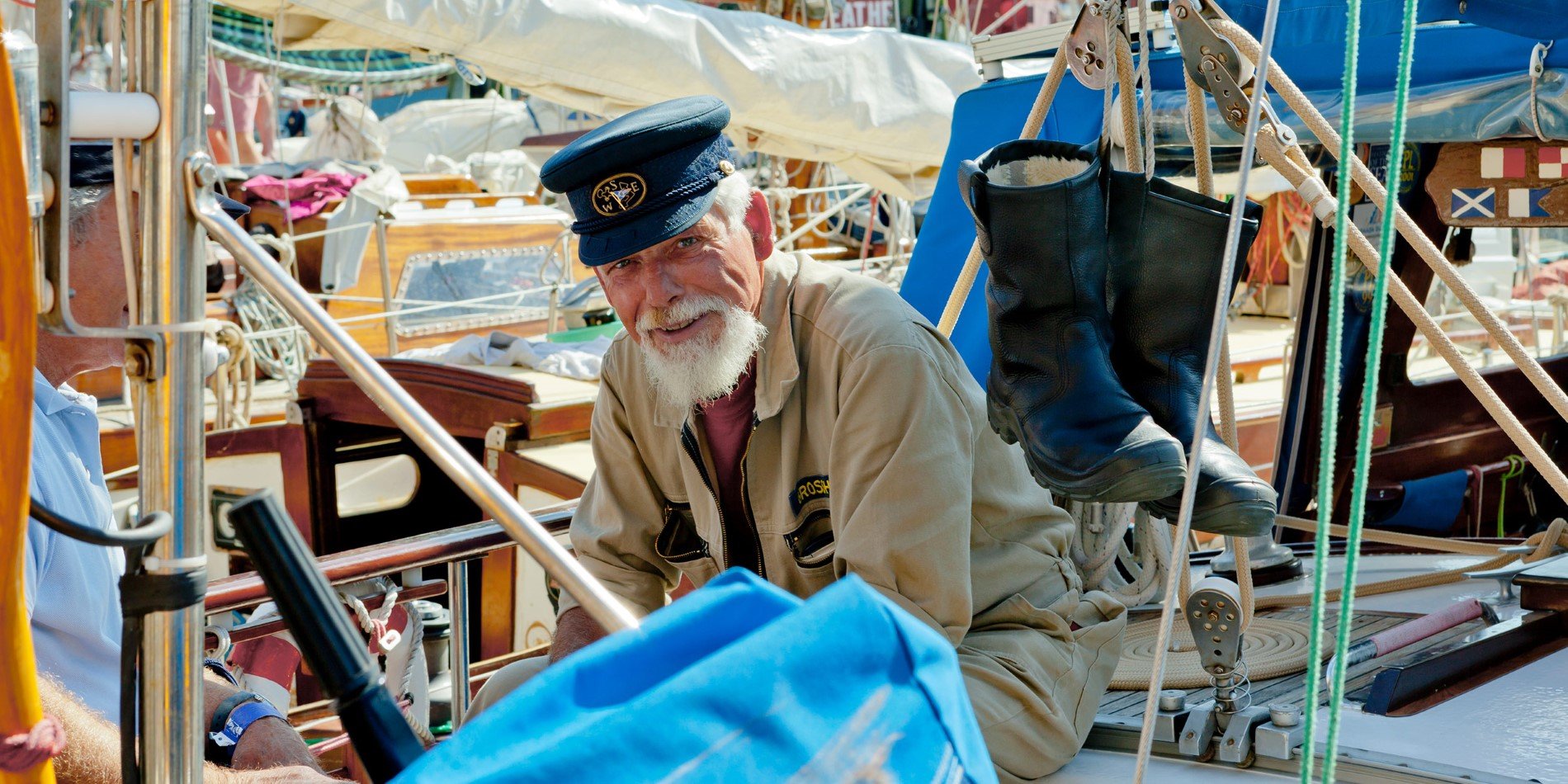 Sailor with white beard and blue hat on board a ship.
