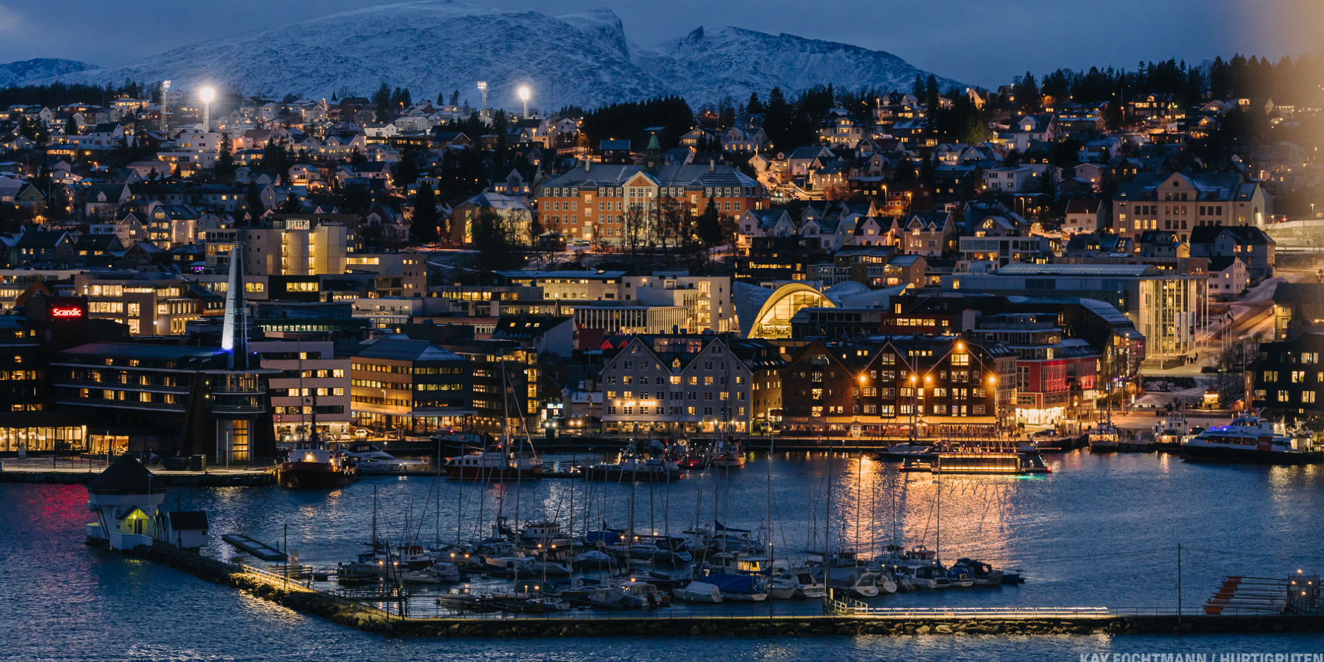 Photo of Tromsø at night. The vibrant city lights are glowing