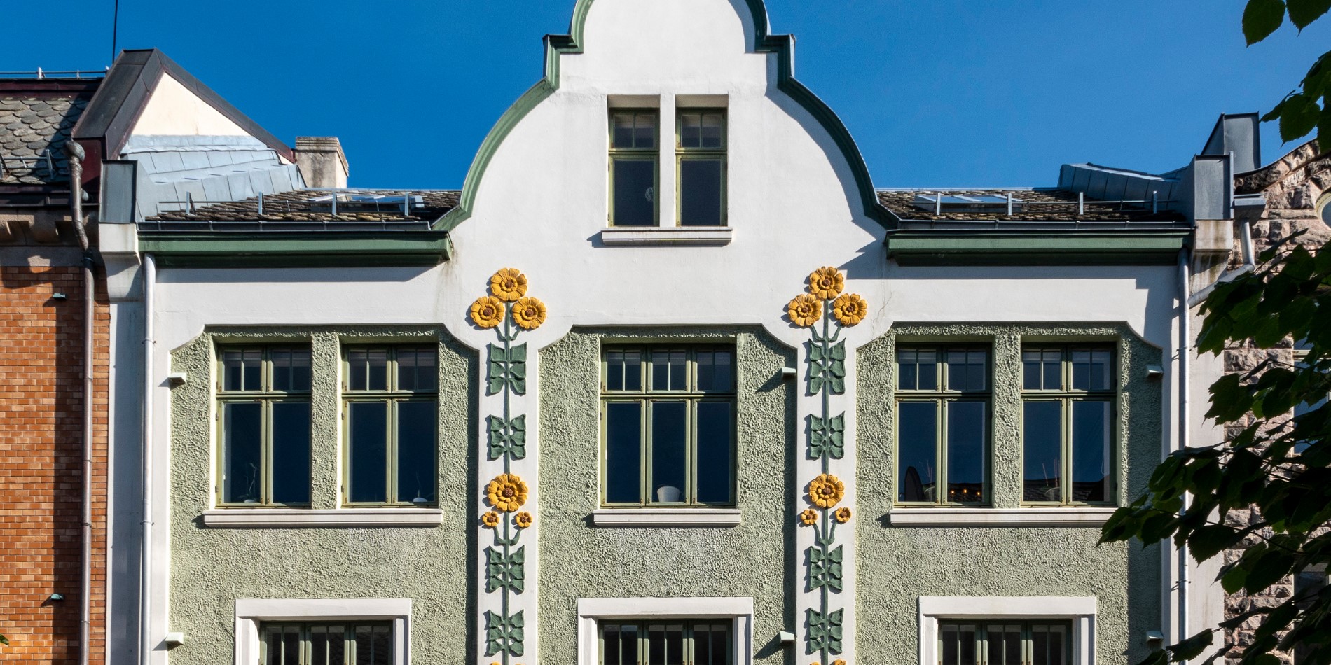 Green building with pink flowers on it, building on the Art Nouveau walk in Aalesund