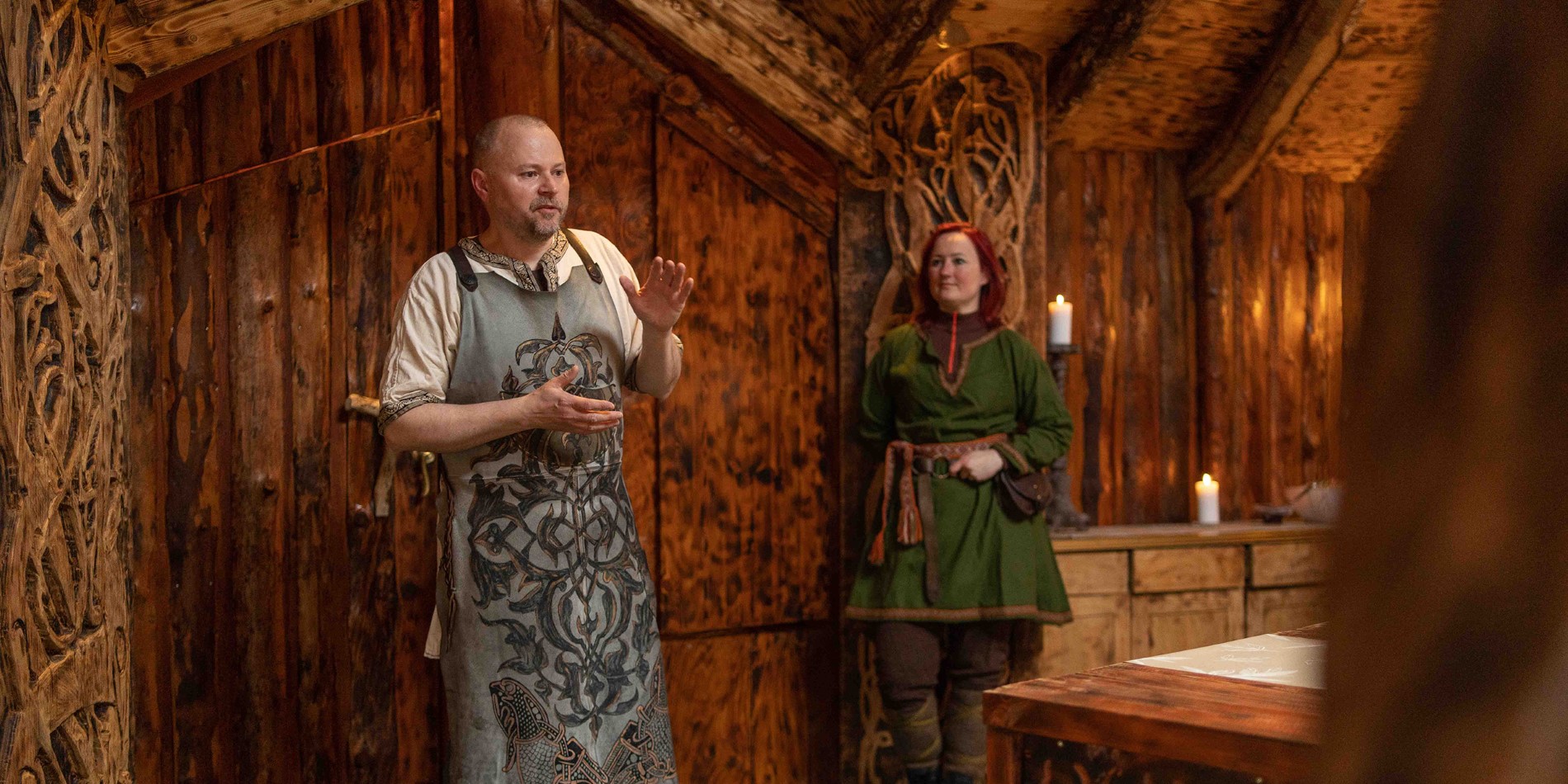 Two instructors inside a viking house in Tromsø, teaching the visitors about the viking culture.