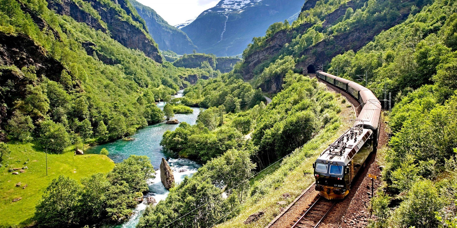 Flåm railway in a warm summer day, the trees are green and the river is blue