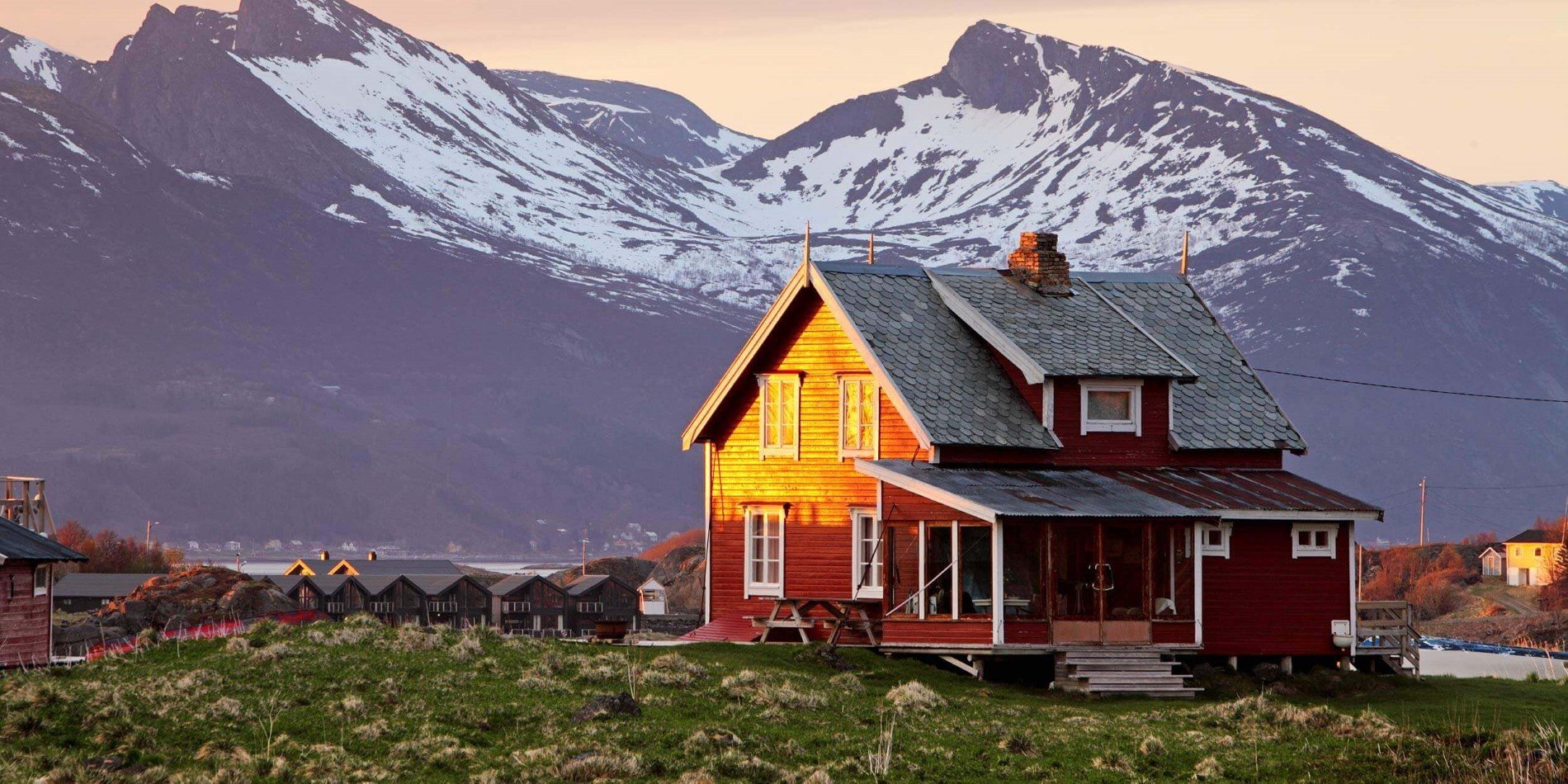 Red house in low sunlight with beautiful mountains in the background