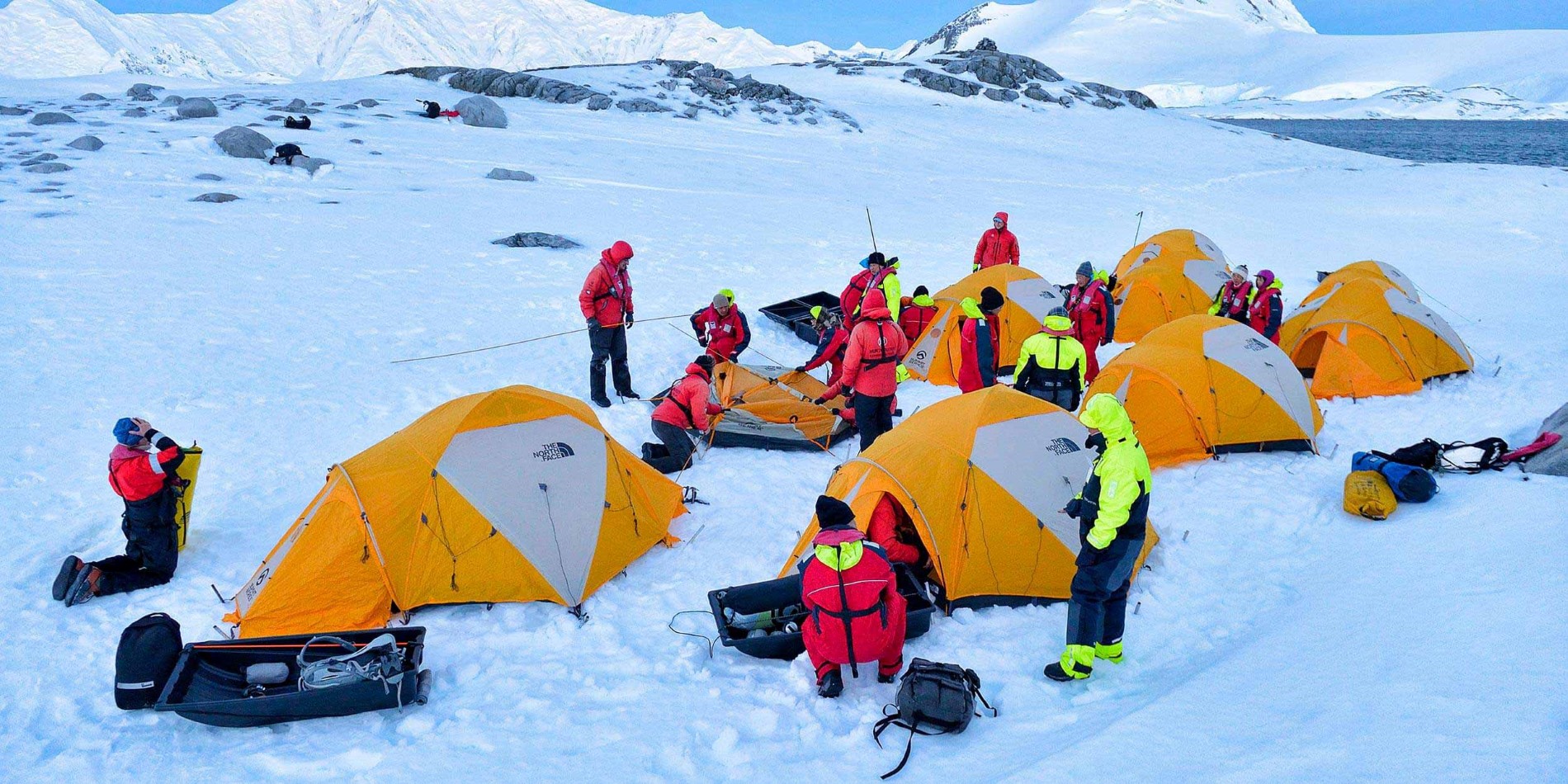 Group of tents being raised in a snowy antarctic landscap